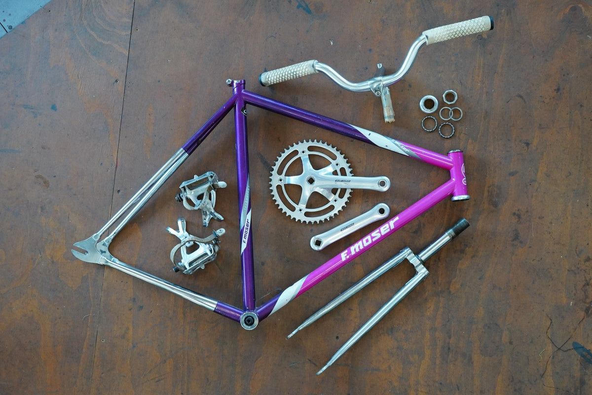 F Moser bicycle frame and components on a wooden surface